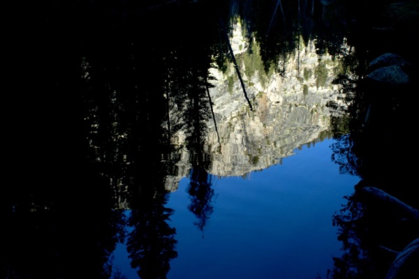 A granite peak is reflected in the Merced River yosemite backcountry wilderness merced river