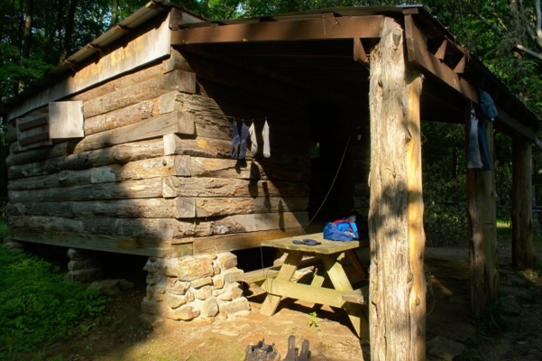 The Ohio River Shelter offers several picnic tables, fire rings, and a cabin with shuttered windows and a door! indiana adventure hiking trail ohio river shelter