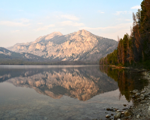 The glassy Pettit Lake reflects distant peaks pettit lake sawtooth mountain wilderness