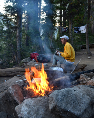 Dad enjoys dinner on the banks of Middle Cramer Lake backpacking camping sawtooth mountain wilderness