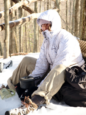 Cedar warms her hands while keeping the wind away from the camp stove winter camping shenandoah national park backpacking