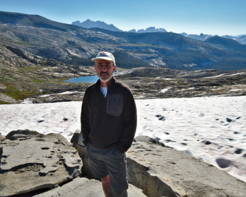 Dad poses for a photo on top of Isberg pass with Inyo National Forest, Mount Ritter and the Minarets in the distance behind him isberg pass inyo view