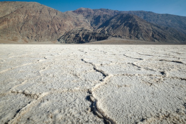 Out on the floor of Death Valley, the ground is caked with salt crystals. The geometric patterns shown here cover the landscape and mirror the cracked mud beneath the salt. death valley badwater basin salt flat