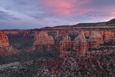 The last light of day casts a colorful glow over the canyon walls and spires. This image is available for purchase from our <a href='https://shop.backcountrysights.com/product/monument-valley/'>shop</a>. colorado national monument sunset