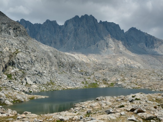 Imposing peaks and stormy clouds tower above one of the Barrett Lakes sierra high route palisades