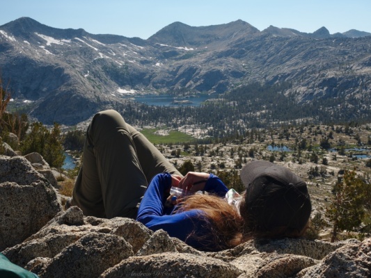 Amanda relaxes at the top of the pass while admiring the sparkling waters of distant Granite Lake sierra high route grouse lake pass