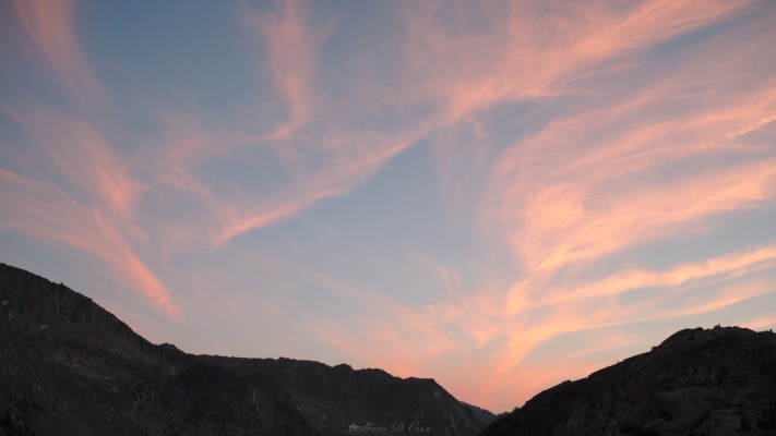 Wispy cloud tendrils glow pink at sunset sierra high route sunset