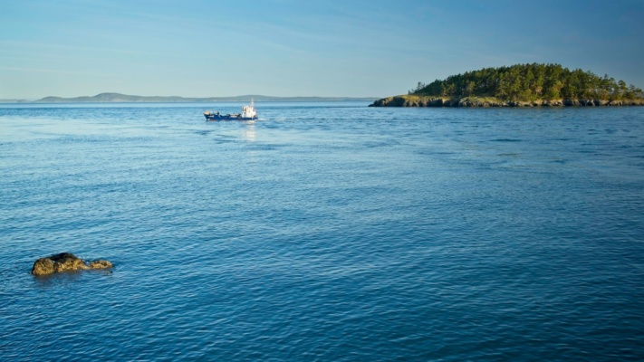 A boat heads out to sea shortly after sunrise deception pass boat