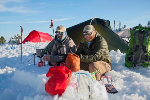 Zak and Brian cook dinner on their snow-table mount backer winter camping