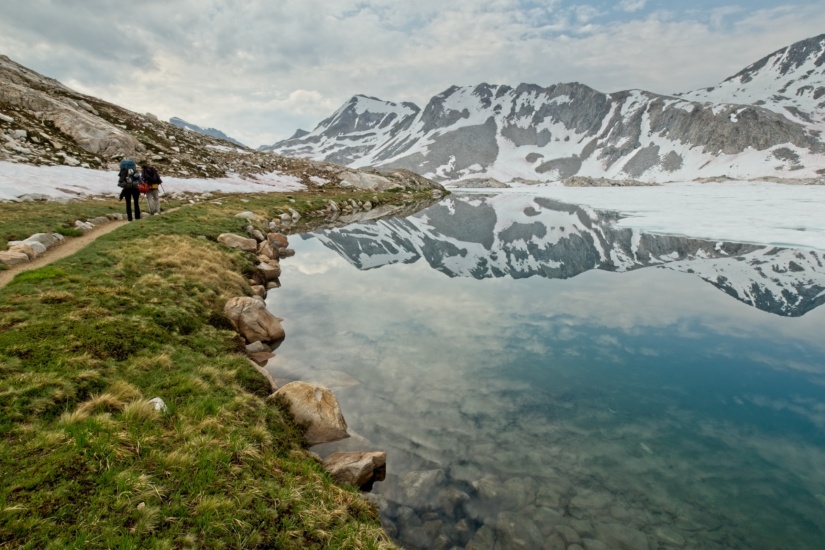 Two backpackers walk southbound on the John Muir Trail along the banks of Wanda Lake. sierra nevada john muir trail