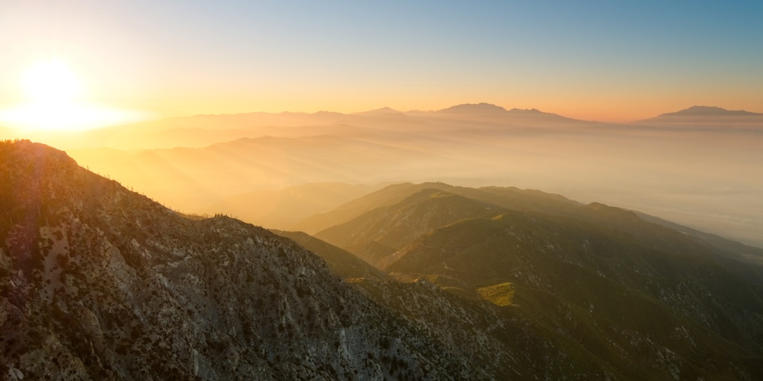 The rising sun sends rays streaming through the misty air around Cucamonga Peak. cucamonga peak sunrise