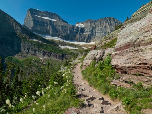 The path leads to Grinnell Glacier, the large swatch of snow and ice beneath the cliffs in the distance. glacier national park grinnell trail