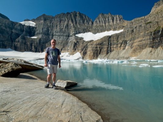 Steve poses in front of the teal water glacier national park grinnell