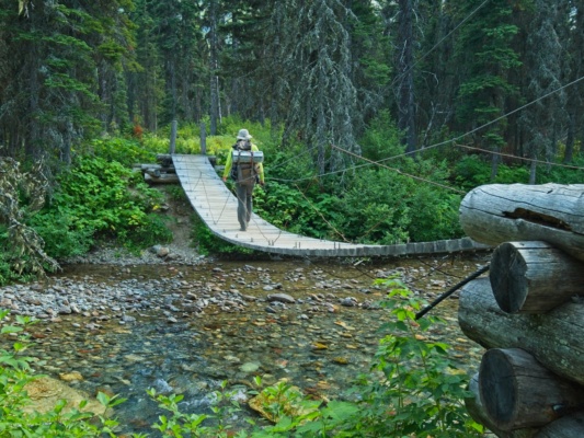 Steve crosses the suspension bridge over Reynolds Creek glacier national park backpacking