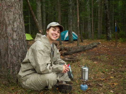 Emily heats water for dinner camping