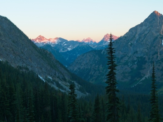 The rising sun illuminates distant peaks beckey route liberty bell