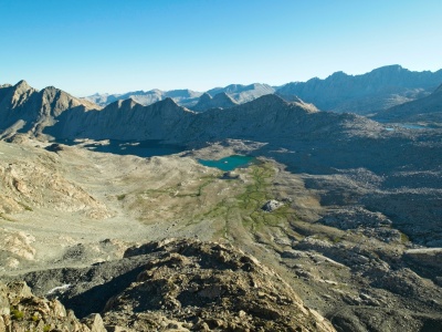After climbing for a while, the sun makes it over the ridge to illuminate the basin below Mount Goddard davis lake basin