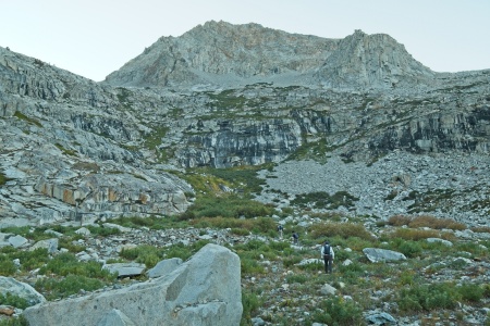 Craig, Kathy, and Ron bushwhack through the meadow toward the headwall lion rock