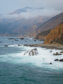 Water from a crashing waves pours off a rock big sur