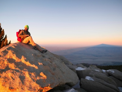 Alex rests on the summit with the shadow of the mountain stretching out behind him san jacinto summit
