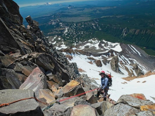 Linda rappels down the rock to the top of the snow mount jefferson mountaineering