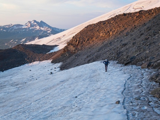 Linda strolls up a snowfield toward the saddle glacial terrain