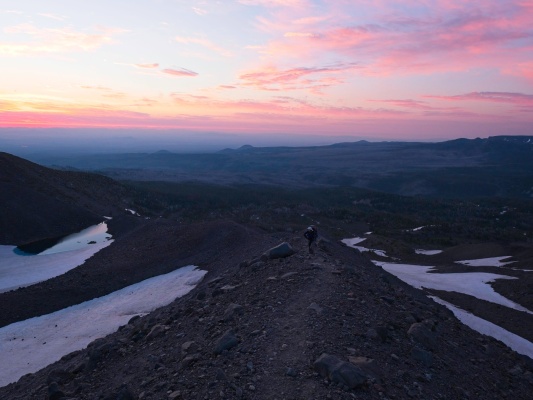Linda hikes up the moraine with sunrise behind her sunrise