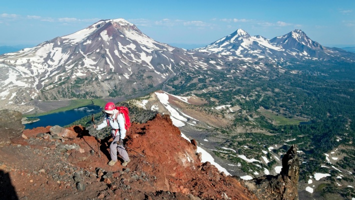 Linda hikes up the north ridge of Broken Top with the Three Sisters in the background three sisters