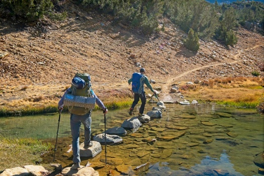 Josh and Alex hop across a string of rocks creek crossing