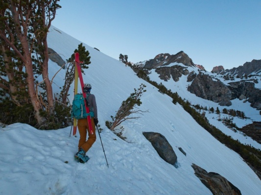Erica begins across the steep slope as first light hits the Sierra crest ski mountaineering