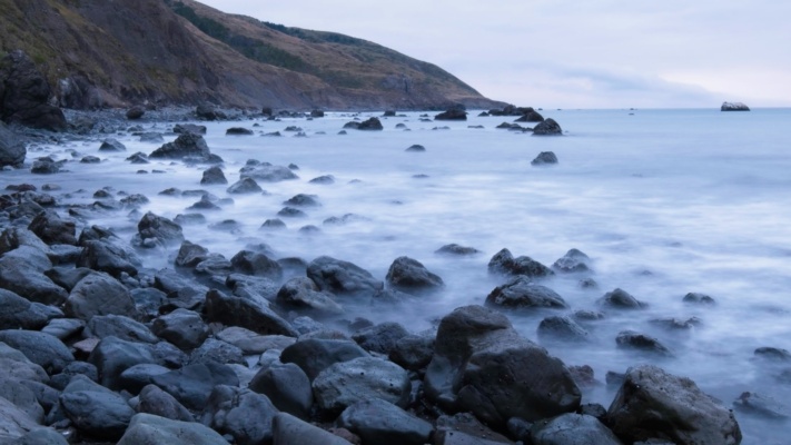A long exposure of the waves washing over the rocky shore ocean long exposure