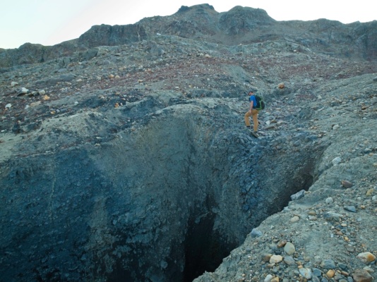 A deep gorge through the dirt-ice matrix glacial landscape
