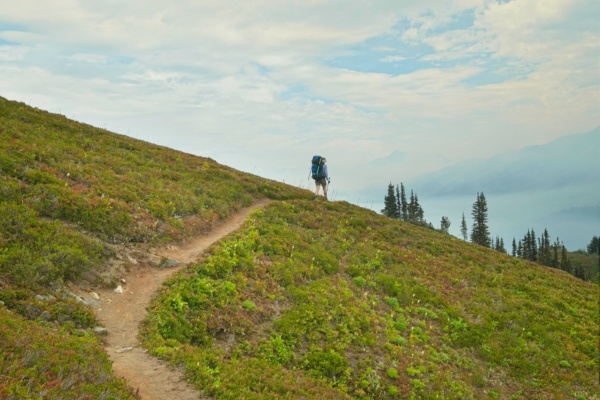 Dagmar hikes over the hill toward a smoke-filled valley glacier peak trail