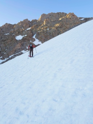 Early morning light hits the rocks above the snowfield ski tour