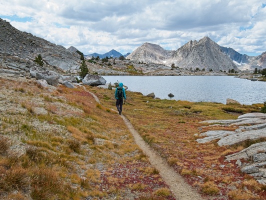 Craig hikes past one of the lower lakes; The Hermit is the peak on the right darwin bench